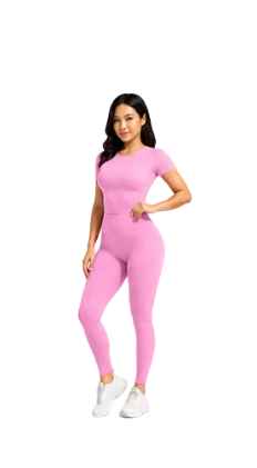 A woman modeling a bright pink short-sleeve athletic jumpsuit with white sneakers, standing against a light gray studio background.