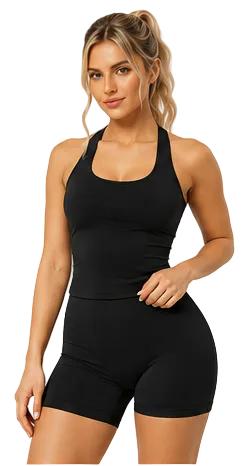 A woman modeling a black athletic tank top and matching high-waisted biker shorts against a plain light beige studio background.