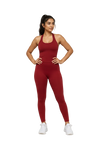 A woman modeling a matching red athletic tank top and high-waisted leggings set, paired with white sneakers, against a plain white background.