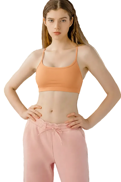 Woman wearing a black sports bra and pink pants on a white background